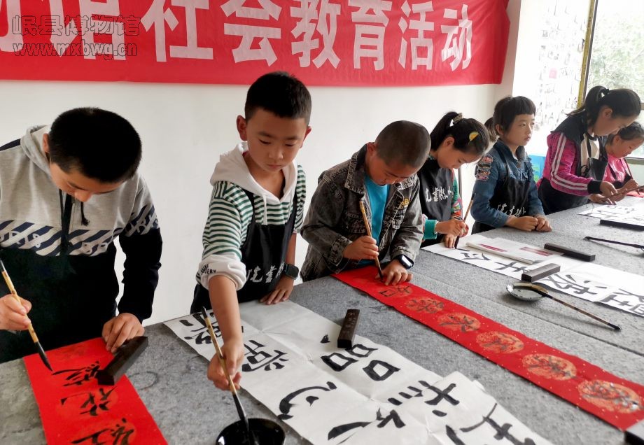 孩子们在应邀的书法老师手把手指导下书写楹联